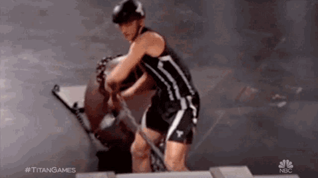 a man in a black and white tank top and shorts is standing on a stage holding a sword .