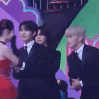 a woman in a red dress is standing next to a man in a suit and tie on a stage .