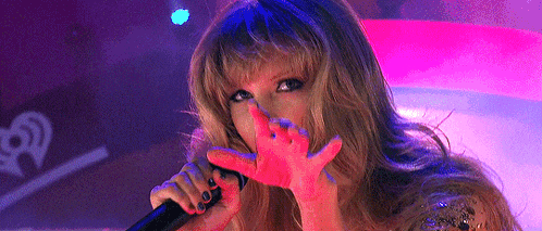 a woman is singing into a microphone and covering her face with her hands .
