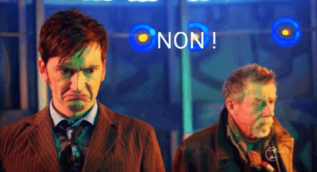 two men are standing in front of a blue sign that says non