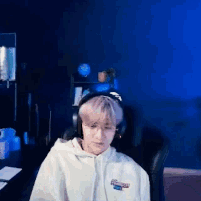 a man wearing headphones and a white hoodie is sitting in a chair .