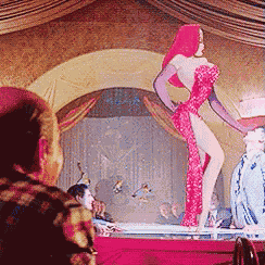 a woman in a red dress and gloves is dancing on a stage .