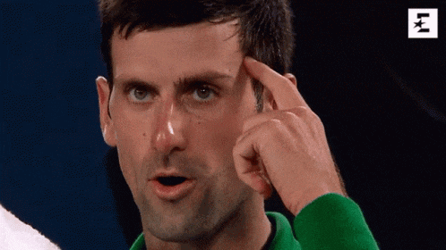 a man in a green sweater is pointing at his head