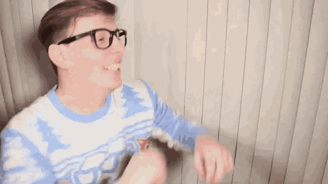 a man wearing glasses and a blue sweater is asking can i have another one ?