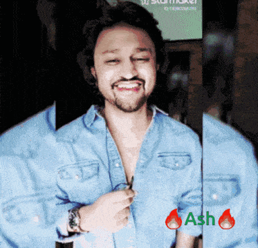 a man with a beard wearing a denim shirt is smiling with ash written on the bottom right