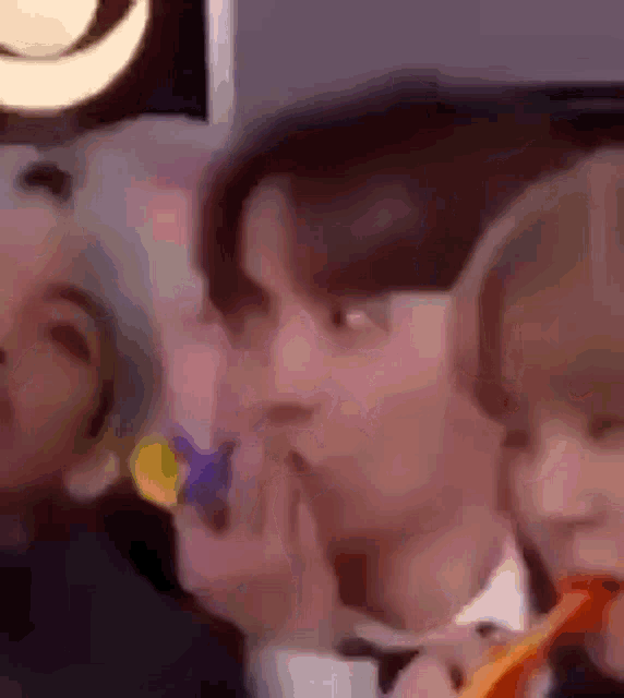 a group of people are sitting next to each other and one of them is holding a lollipop .