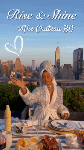 a woman in a bathrobe is sitting at a table with a city in the background and the words rise & shine at the chateau