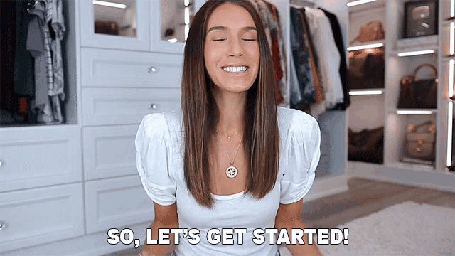 a woman in a white shirt is sitting in front of a closet and says so let 's get started