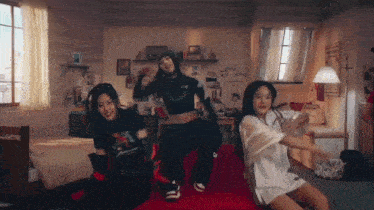 three girls are dancing together in a bedroom with a bed