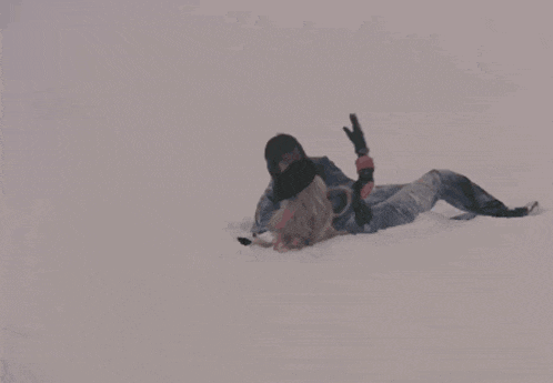 a man is kneeling down next to a woman laying on the snow