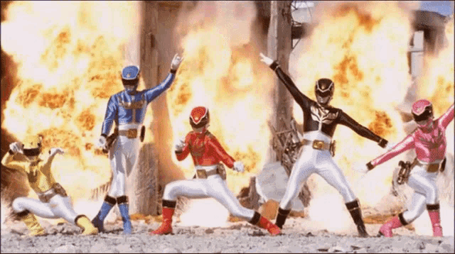 a group of power rangers are standing in front of a large explosion