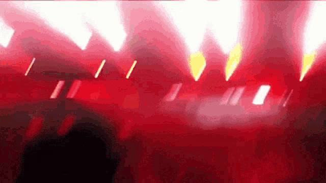 a crowd of people are dancing in a dark room with red lights shining on them .