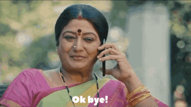 a woman in a pink sari is talking on a cell phone .