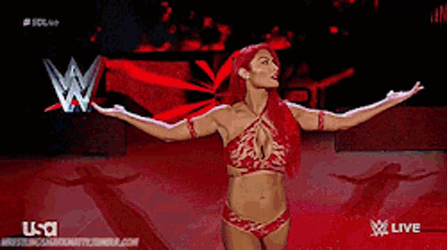 a woman in a red bikini is standing on a stage with her arms outstretched in front of a w logo .