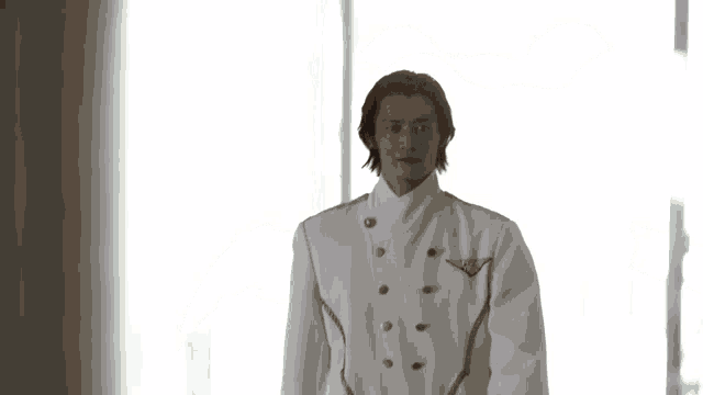 a blurry picture of a person standing in front of a window behind a curtain .