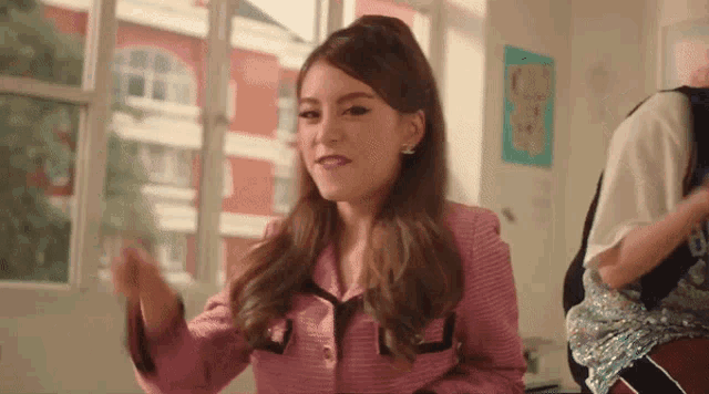 a girl in a pink jacket is sitting in front of a window .