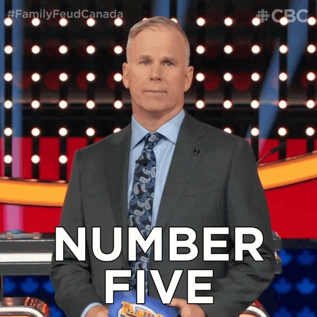 a man in a suit and tie stands in front of a podium with the words number five on it