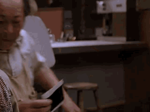 a woman is sitting at a table holding a piece of paper in her hand .