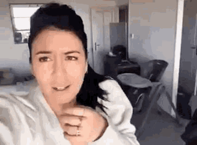 a woman is taking a selfie in a living room while wearing a white robe .