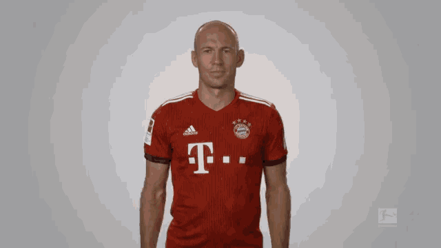 a bald man wearing a red adidas shirt with the letter t on it