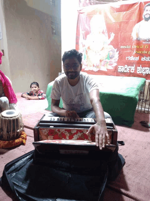 a man is playing an accordion in front of a banner that says ' kannada ' on it