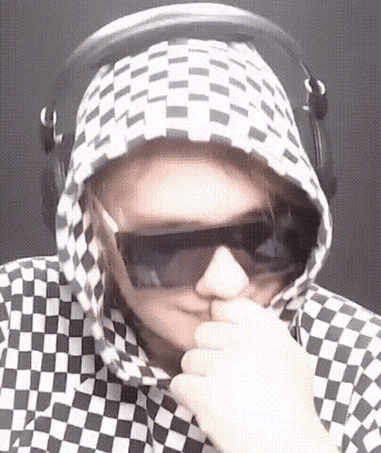 a person wearing sunglasses and a checkered hoodie covering their face