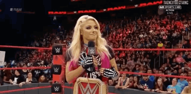 a woman is standing in a wrestling ring with a microphone in her hand .
