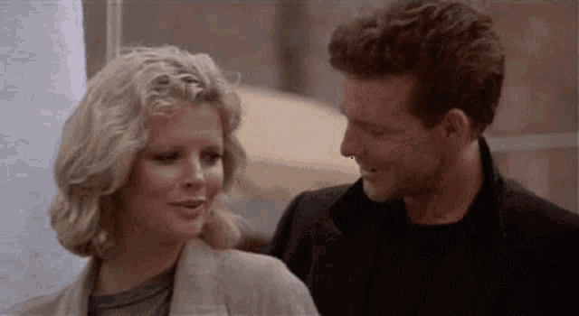a man and a woman are looking at each other and smiling while standing next to each other .