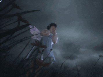 a girl with fairy wings is standing in the dark