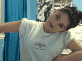 a girl wearing a white t-shirt that says jansport stands in front of a blue curtain