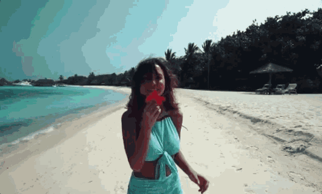 a woman in a blue top and skirt is walking on the beach
