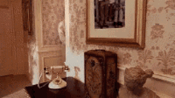 a telephone is sitting on a wooden table in a room next to a statue .