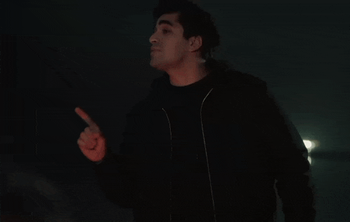 a man in a black jacket points his finger up