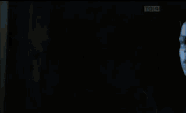 a man in a suit and tie is standing in a dark room with his mouth open .