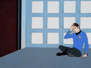a man in a blue shirt is sitting on the floor with his hands on his head