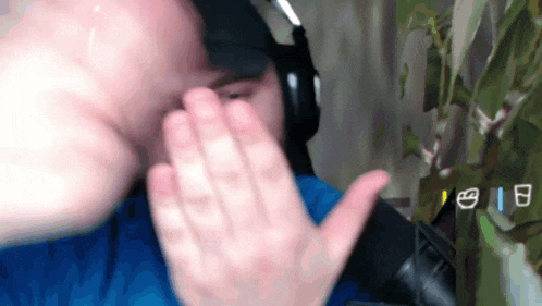 a man wearing headphones and a blue shirt is covering his face with his hands