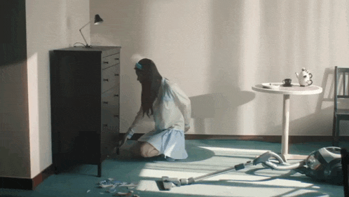 a woman kneeling on the floor with a vacuum cleaner in front of her