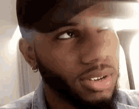 a close up of a man with a beard wearing a hat and gold teeth .