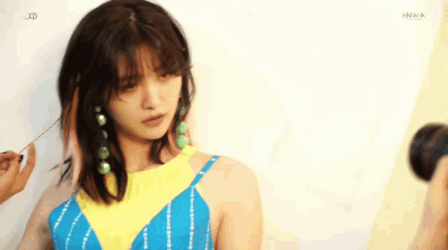 a woman in a blue and yellow dress is being photographed by a camera with the word hana on the bottom