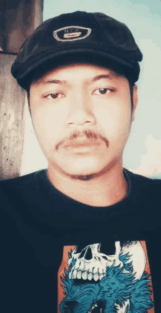 a man wearing a hat and a t-shirt with a skull on it