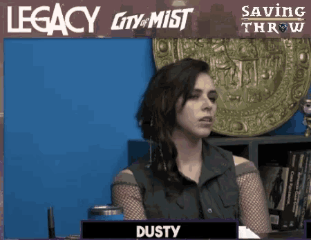 a woman is sitting in front of a legacy city of mist sign