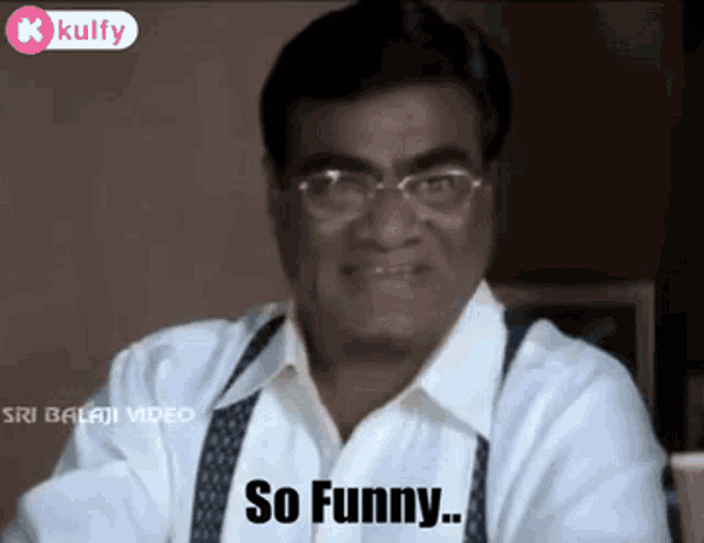 a man in a white shirt and suspenders is sitting at a table and says so funny .