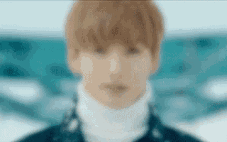 a close up of a person 's face with a turtleneck and a blurred background .