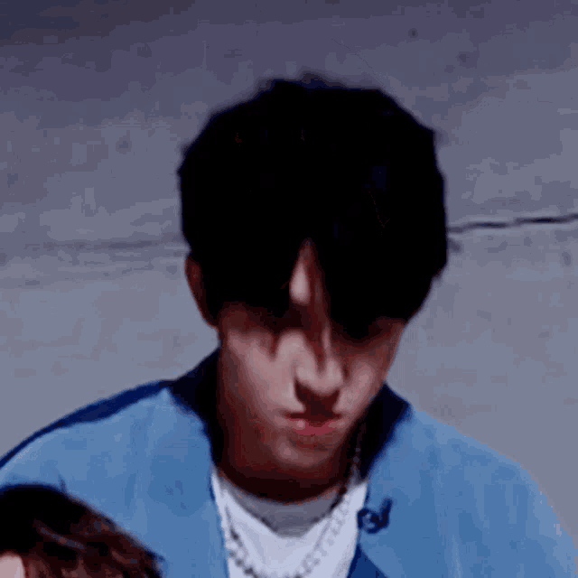 a close up of a young man wearing a blue jacket and a white shirt .