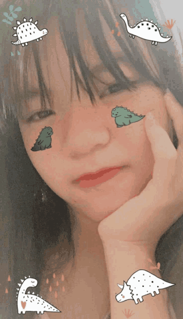 a girl with stickers of dinosaurs on her face looks at the camera