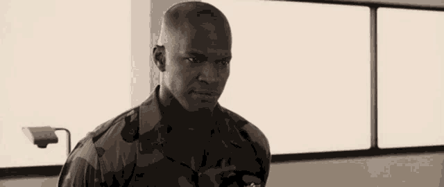 a man in a military uniform is standing in a room with a lamp .
