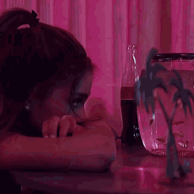 a woman is sitting at a table with a bottle of coke and a fish bowl