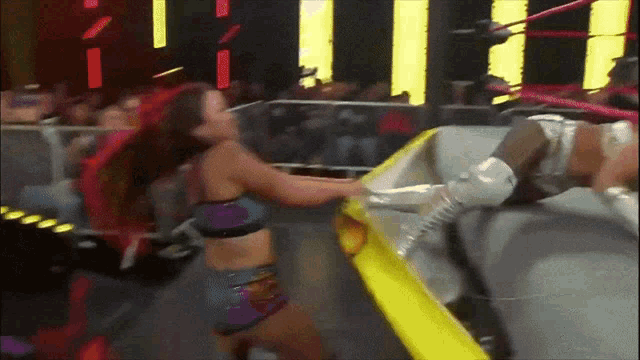 two women are wrestling in a ring and one of them is wearing a purple top