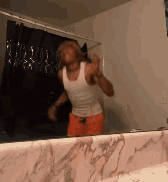 a man is dancing in front of a bathroom mirror