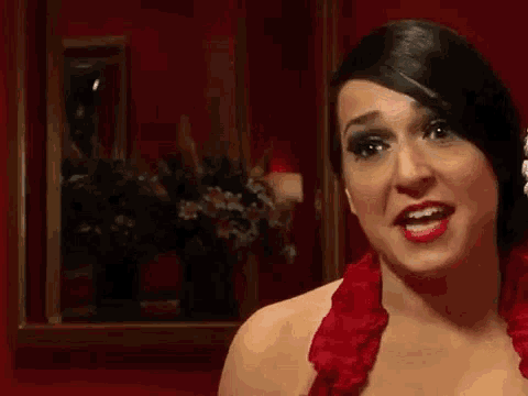 a woman in a red dress is looking at the camera .